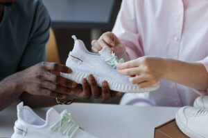 Mâinile unui tânăr bărbat și ale unei femei care despachetează un colet cu sneakerși noi comandați în magazinul online care vinde îmbrăcăminte sportivă