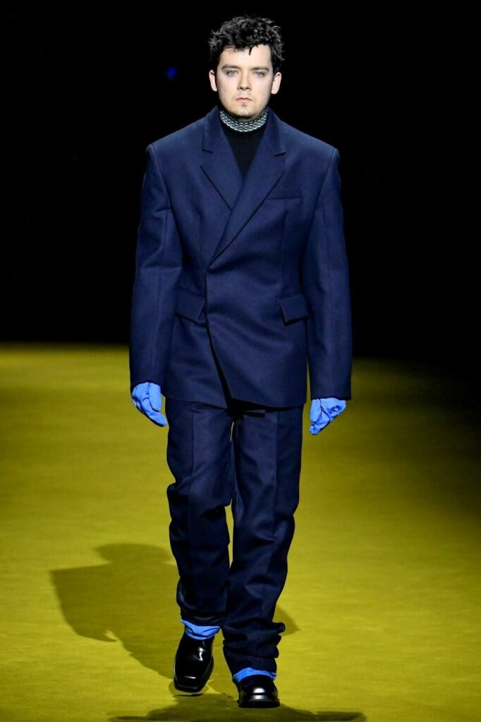 Bărbat cu costum bleumarin, mănuși albastre și pantofi negri