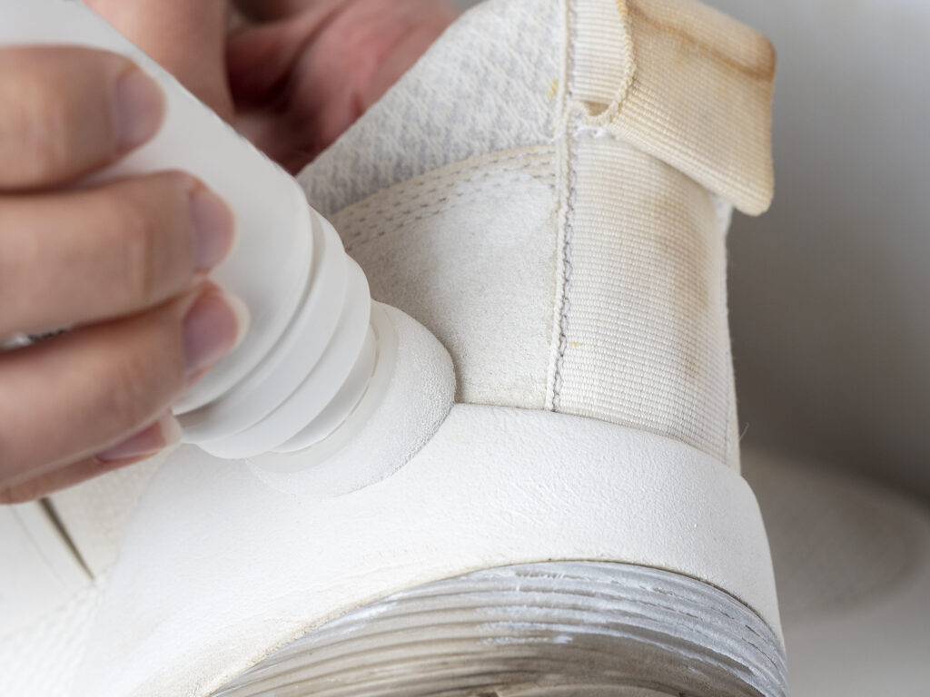 Curățarea unui preparat special cu un burete dintr-un pantof sport alb: talpa
