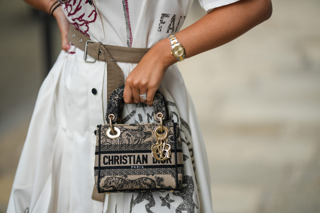 PARIS, FRANCE - AUGUST 26: Gabriella Berdugo wears a white latte with embroidered burgundy and gray pattern short sleeves / buttoned / slit midi dress, a beige belt, a beige and blue embroidered pattern Lady D-light handbag from Dior, during a street style fashion photo session, on August 26, 2022 in Paris, France. (Photo by Edward Berthelot/Getty Images)