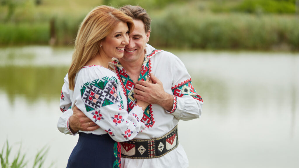 Profile portait of a happy couple wife and husband together embracing posing in Romanian national clothes.