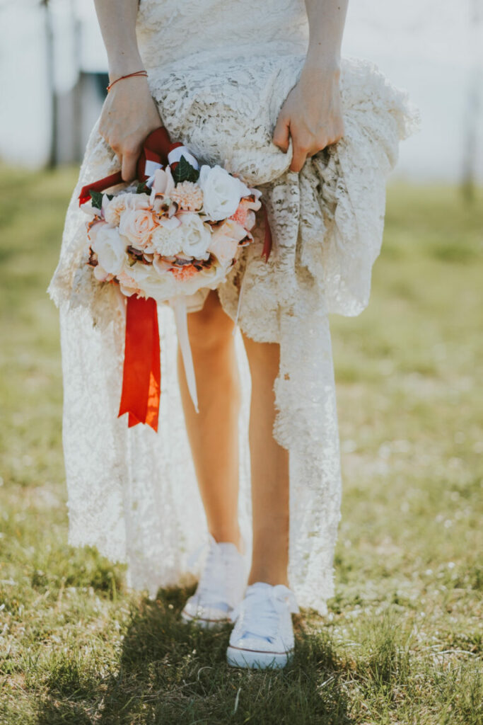 O mireasă cu o rochie albă din dantelă și teniși albi