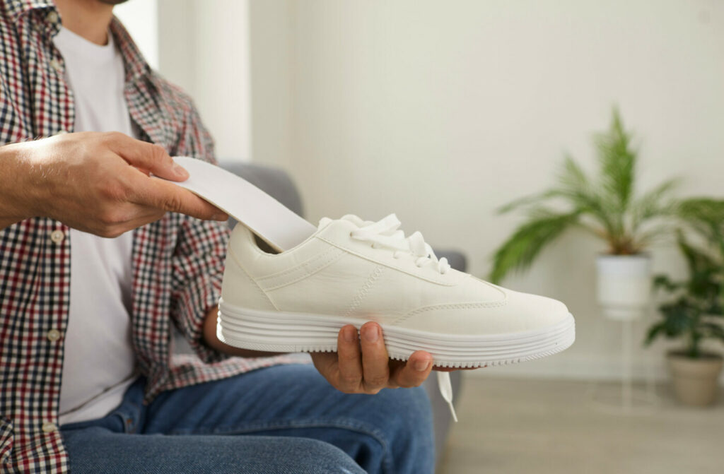 un bărbat ține în mână sneakerși albi