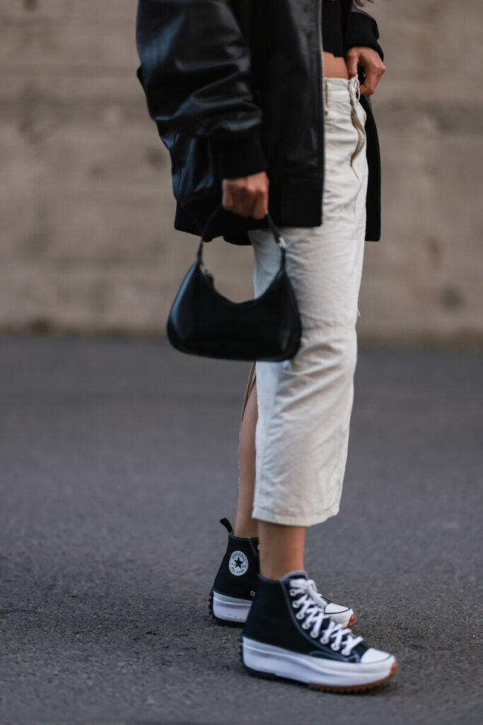 o femeie poartă teniși Converse negri cu platformă