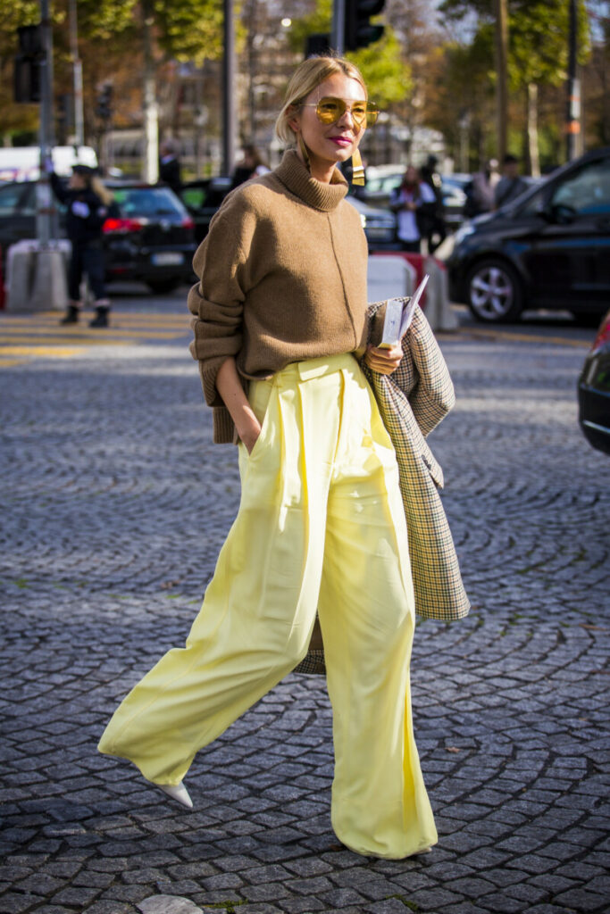 o femeie poartă pantaloni galben largi, pantofi stiletto și o bluză maro