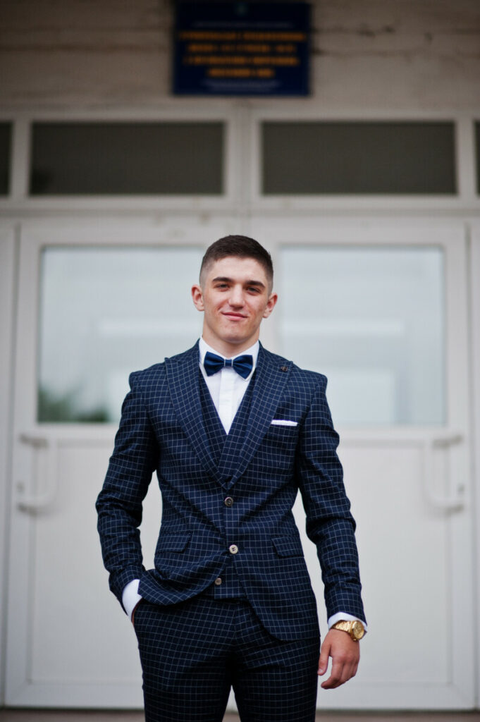 Tânăr purtând un costum în carouri albastru marin cu papion în loc de cravată