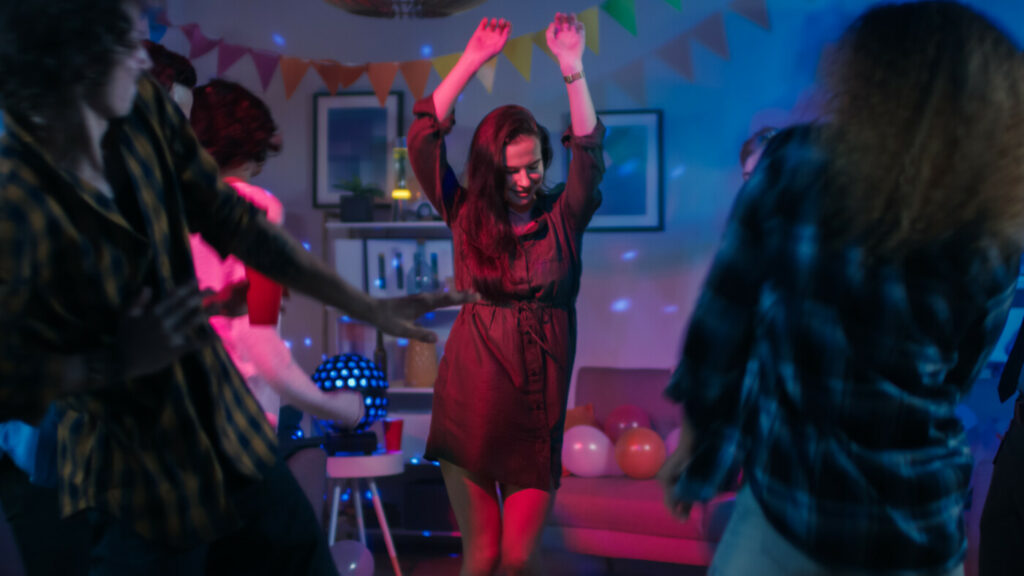 Fata care dansează la o petrecere aniversară, purtând o rochie de cămașă