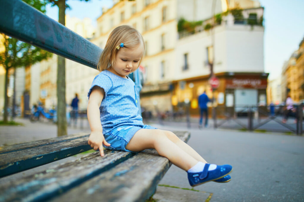 O fetiță stă pe o bancă